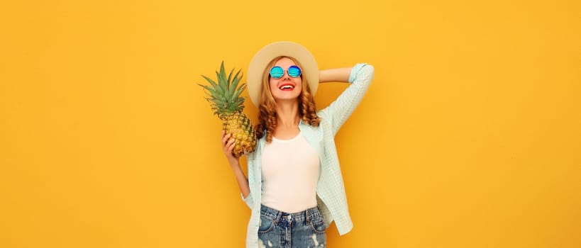 Summer vacation, happy joyful young woman with pineapple fruit in tourist hat, cheerful girl posing on yellow studio background