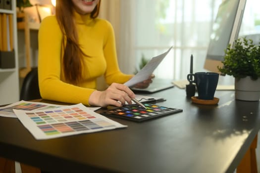 Smiling young graphic designer working with color swatches in a creative office.