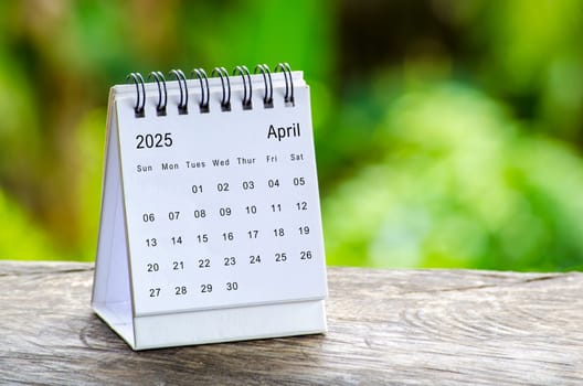 April 2025 white table calendar with outdoor background. Calendar concept.