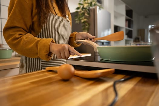 Young woman wearing striped apron preparing meal in a stylish modern kitchen.