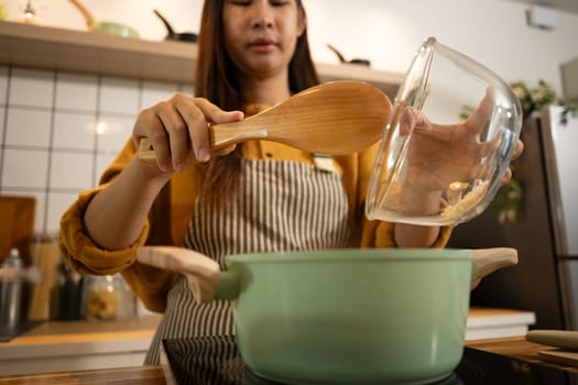 Young woman wearing striped apron preparing meal in a stylish modern kitchen.