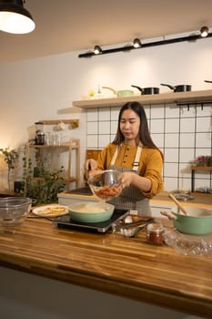 Young Asian woman preparing meal on an Induction stove in a kitchen.
