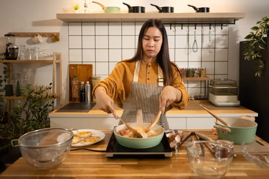 Young woman wearing striped apron preparing meal in a stylish modern kitchen.