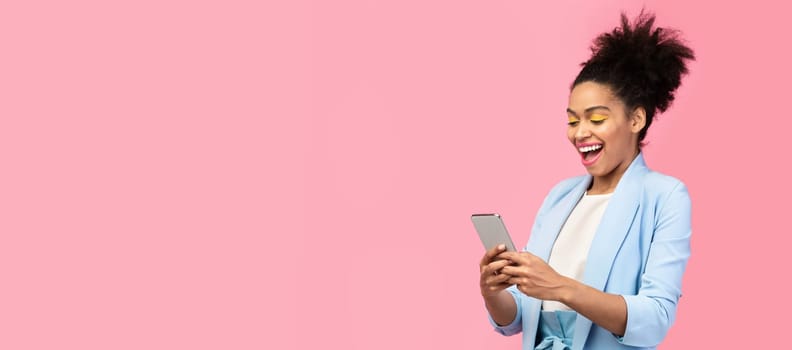 Amazing Application. Happy young black woman using cell phone isolated over pastel pink studio wall, copyspace