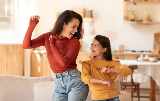 Cheerful Middle Eastern Mother And Daughter Kid Dancing Together At Modern Kitchen Interior. Young Mom And Preteen Child Girl Having Fun During Home Party Indoors On Weekend