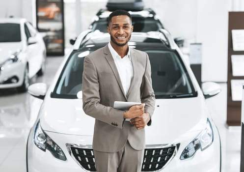 Cars Dealership Concept. Auto Seller Afro Man Smiling To Camera Standing In Automobile Center.