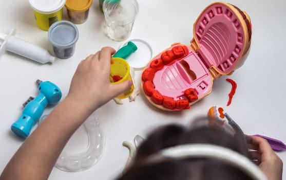 A child plays dentist and makes teeth out of plasticine. High quality photo