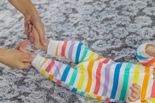 A young mother massages her baby while playing with her on the bed. baby