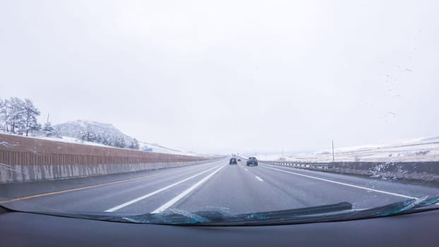 The open highway invites a peaceful drive, with snow-clad pines lining I-25 as the journey continues from Denver towards Colorado Springs on a snowy day.