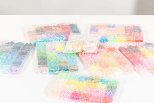 Assorted clay bead boxes neatly arranged on a white table, awaiting a creative kids' craft project.
