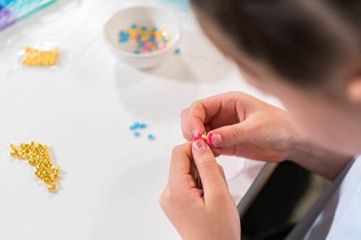 Little girl enjoys crafting colorful bracelets with vibrant clay beads set.