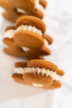 Gingerbread cookies filled with eggnog buttercream stand out, their rich hue complementing the eggnog buttercream, against a gentle background. These festive treats exude a homemade allure.