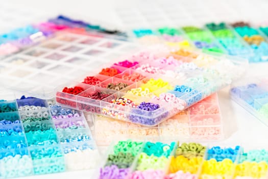 Assorted clay bead boxes neatly arranged on a white table, awaiting a creative kids' craft project.