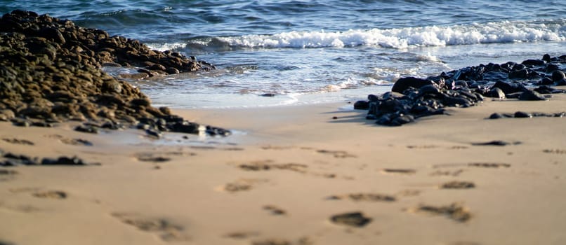 Beautiful seascape in a daylight overlooking water with small waves, volcanic beach on an island in the Atlantic ocean.