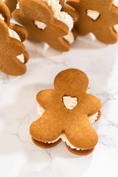Gingerbread cookies filled with eggnog buttercream stand out, their rich hue complementing the eggnog buttercream, against a gentle background. These festive treats exude a homemade allure.