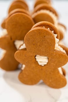 Gingerbread cookies filled with eggnog buttercream stand out, their rich hue complementing the eggnog buttercream, against a gentle background. These festive treats exude a homemade allure.