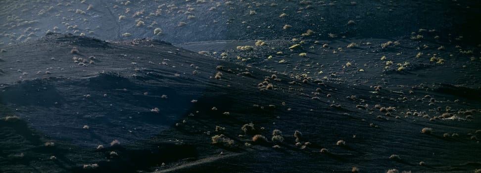 Black fossilized lava formations, basalt rocks close-up at the foot of a volcano on a volcanic beach.