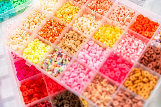 Assorted clay bead boxes neatly arranged on a white table, awaiting a creative kids' craft project.
