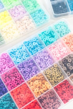 Assorted clay bead boxes neatly arranged on a white table, awaiting a creative kids' craft project.