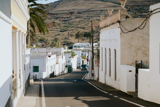 Picturesque streets of a small cozy town with white houses against the backdrop of mountains, view of the road among beautiful buildings on the island of Lanzarote, Canary Islands.