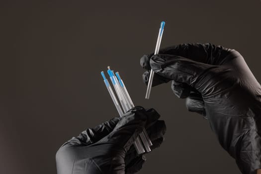 concept dry needling method. Close-up of black-gloved hands holding sterile acupuncture needles in protective tubes, symbolizing alternative medicine, precision, and healthcare.