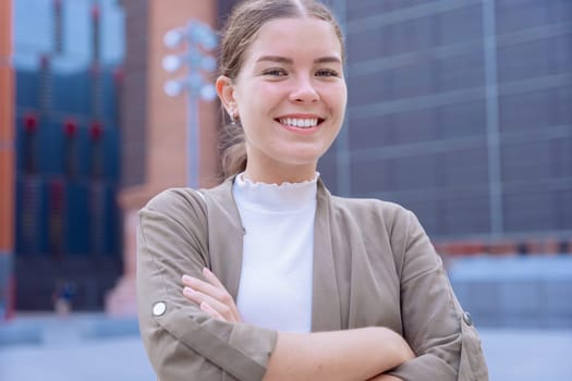 A smiling young businesswoman with her arms crossed looking at the camera. She looks confident and approachable, making her an ideal image for business, leadership, success, and empowerment concepts.