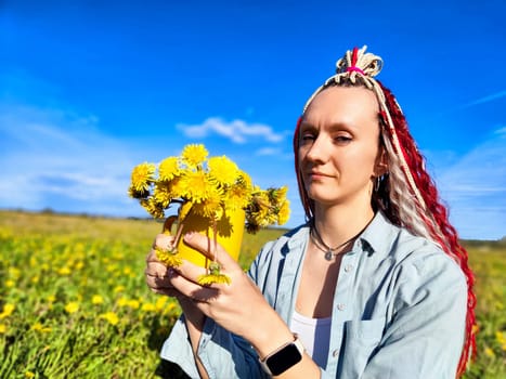 A woman with colorful hair styles delicately holds a jar filled with vibrant dandelions against a blue sky backdrop.