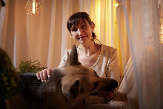 In a warm and inviting apartment, a middle-aged woman finds comfort and joy while spending a quiet evening with her beloved dog.