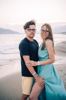 A smiling couple shares a joyful moment on the beach at sunset, the man and the woman near the sea waves, Alanya, Turkey
