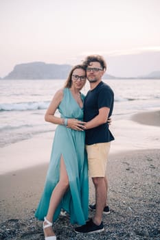 A smiling couple shares a joyful moment on the beach at sunset, the man and the woman near the sea waves, Alanya, Turkey