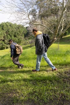 Two biologists walking in a field doing field work, carrying backpacks and wearing casual clothes