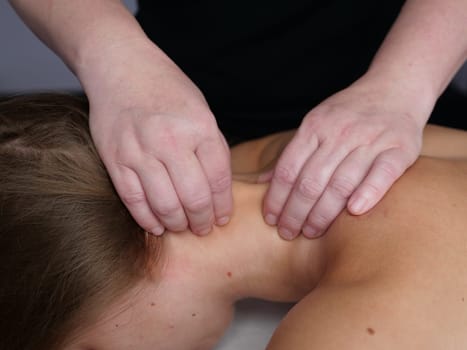 The masseur massages the neck for a woman's client to get rid of pain and discomfort in the body. close-up