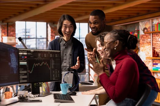 Cheerful multiethnic startup team celebrating high valuation on stock exchange, raising money. Tech business entrepreneurs securing angel investments, becoming unicorn company
