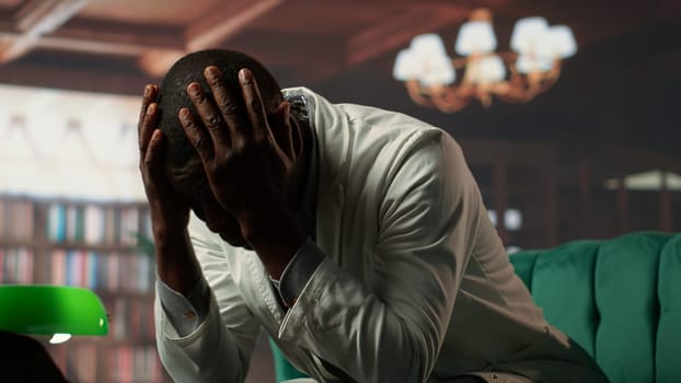 Black physician opening up about hard patient cases and PTSD, psychologist listens carefully in a therapy session. Medic crying and sharing feelings after losing people, trauma support. Camera B.