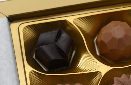Nestled within a golden box, a range of luxurious chocolates awaits, showcasing intricate designs and tempting flavors. Each piece reflects culinary artistry and indulgence.