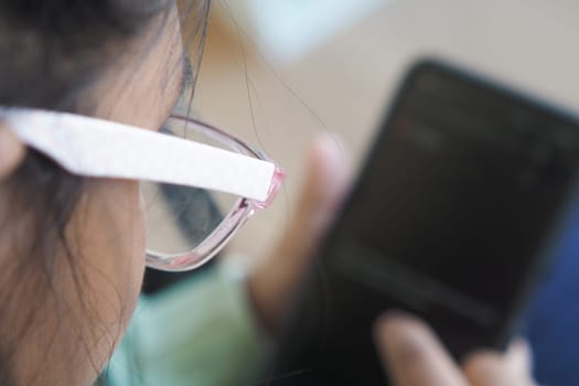 a child using a smartphone while wearing glasses indoors,