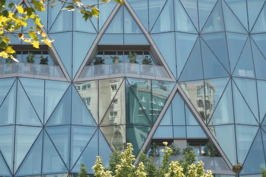 Glass facade showcases intricate geometric patterns and city reflections.