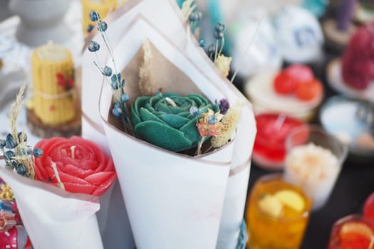 Colorful handmade flower-shaped candles on display.