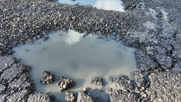 Water accumulates in a damaged road surface following recent rain.