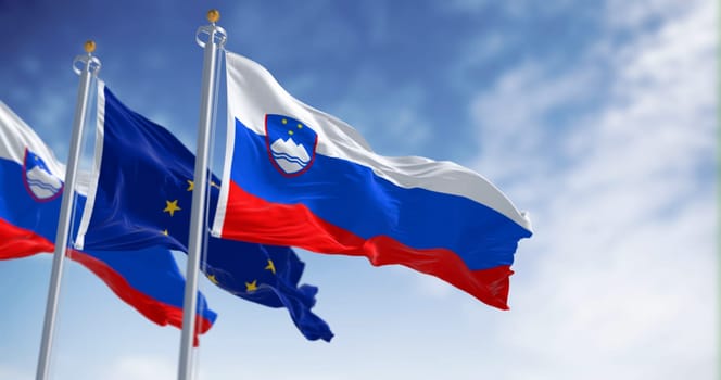 The flags of Slovenia and the European Union fluttering together on a clear day. Slovenia has been a member of the eurozone since January 1, 2007. 3D illustration render. Fluttering fabric