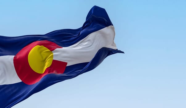 Colorado state flag waving in the wind on a clear day. Three blue, white, and blue stripes. Red C with gold disk on top. 3D illustration render. Fluttering fabric. Selective focus