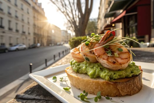 Freshly grilled shrimp sit atop a slice of toasted bread smeared with creamy avocado, displayed on a sunny street patio. The warm light of the sunset enhances the vibrant colors of the dish.