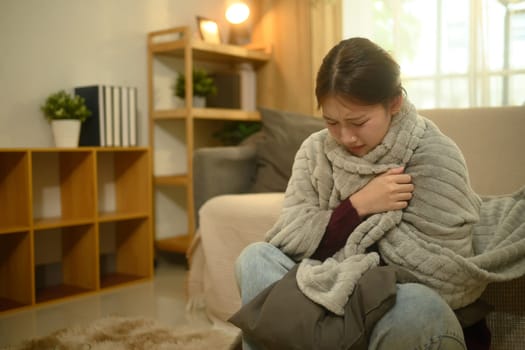 Sick woman wrapped in blanket, suffering from fever or flu.