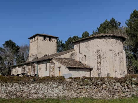 Eglise Saint Pierre stands in Mons, Gironde, France, featuring distinct medieval architecture surrounded by a serene cemetery under a clear blue sky, inviting reflection and exploration.