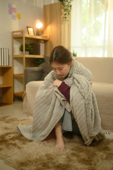 Sick woman wrapped in blanket, suffering from fever or flu.
