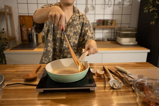 Close up of hands flipping a fried egg in ceramic pan, preparing breakfast in a home kitchen.