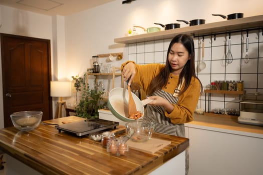 Young asian woman in an apron cooking a simple meal in her home kitchen.