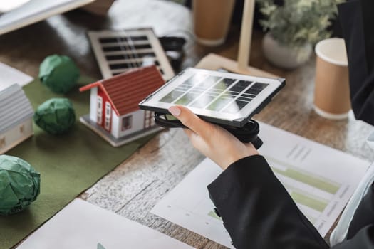 Professionals present solar panels while examining models of eco-friendly homes, highlighting sustainable development in energy solutions.