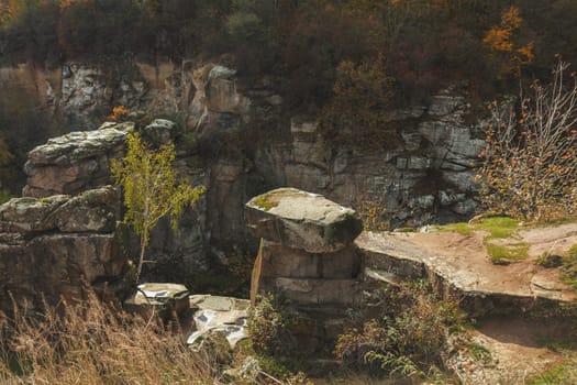 Moss covered rocks and vibrant trees create a breathtaking autumn landscape within an old stone quarry, showcasing nature's colorful beauty