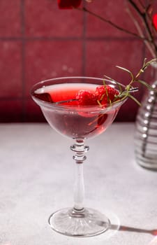 Refreshing red cocktail garnished with raspberries and rosemary sprig, served in a stylish glass against a romantic backdrop, perfect for valentine's day